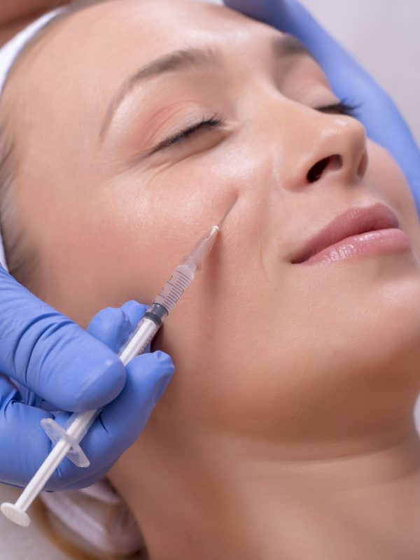 A doctor with rubber gloves doing a plastic face surgery on a happy young female